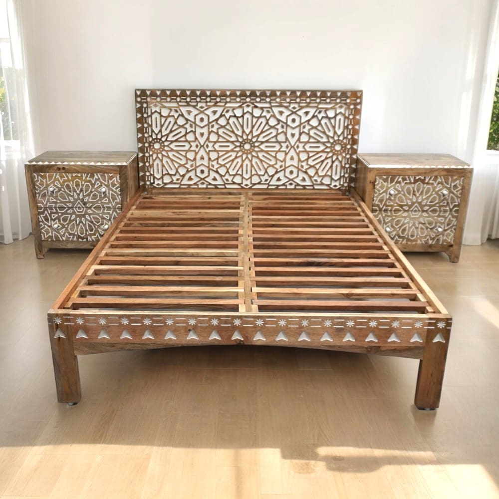 A hand-crafted queen bedframe, solid wood with carved details in a sunny bedroom with matching nightstands sold separately
