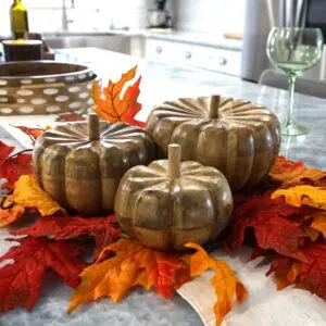 three hand-crafted wood fall pumpkins staged on a kitchen island