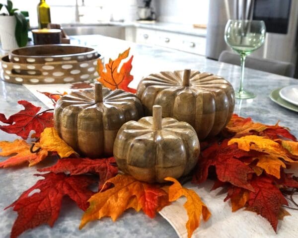 three hand-crafted wood fall pumpkins staged on a kitchen island