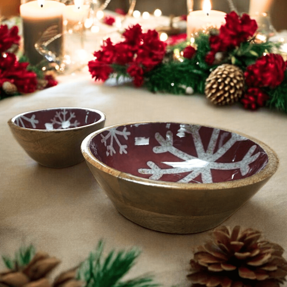 A set of 2 hand-crafted wooden bowls with red enamel and white snowflake pattern staged on a Christmas dinner table