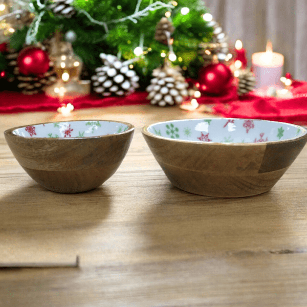 set of two wood bowls with white enamel with green and red snowflake pattern stages on a Christmas table