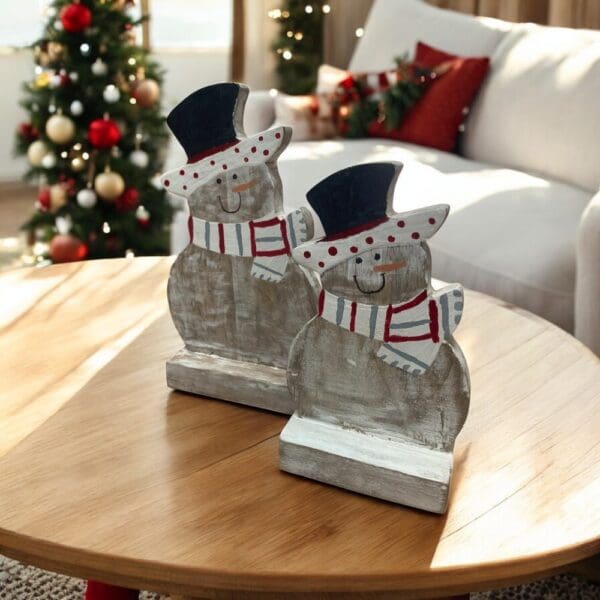 Set of two hand-crafted wooden snowmen with hand-painted detail staged in a living room