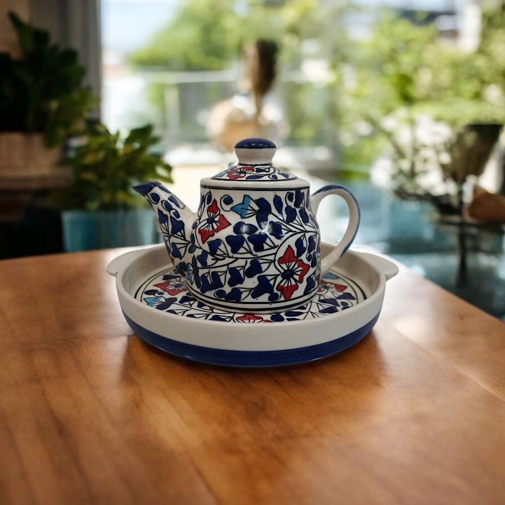 Ceramic teapot with matching round tray staged in a home on a wooden countertop