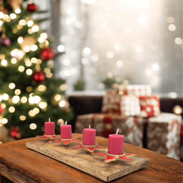 Staged picture of a candle holder, 4 metal stars with red enamel on a wooden plinth in a living room