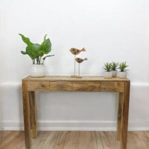 Natural wood console table with a hidden drawer stages with decor items in a hallway