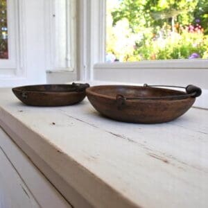 Set of 2 vintage wooden bowls with handles staged on a rustic kitchen counter with a view into a garden
