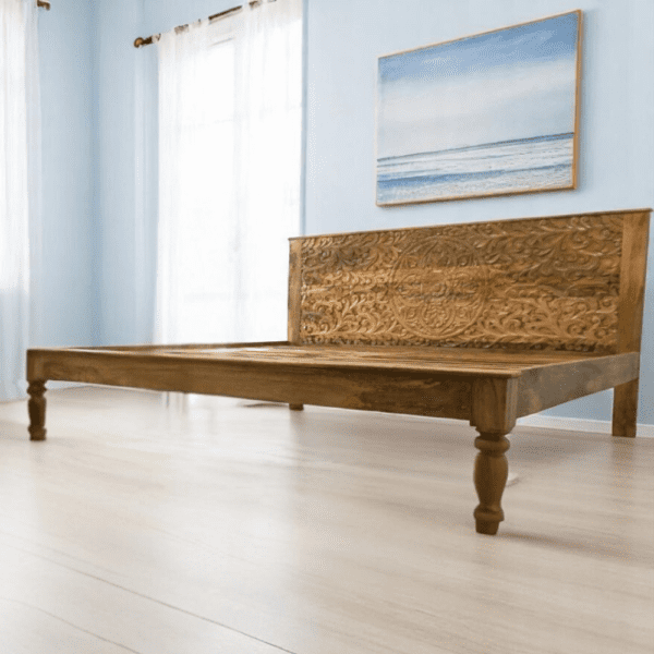 Hand-crafted solid wood king bedframe with hand-carved headboard with a floral mandala design. Staged in a coastal bedroom