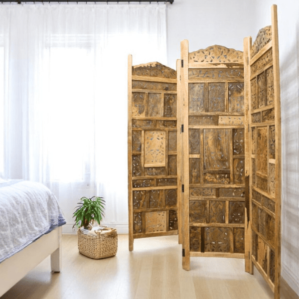 Hand-crafted wood room screen divider with hand-carved cut out detail 72" tall 80" wide when fully extended staged in a sunny bedroom