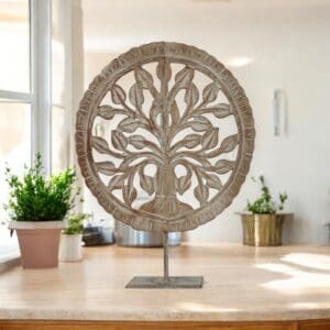 Hand-carved round tree of life decor accent on a metal stand staged in a sunny kitchen
