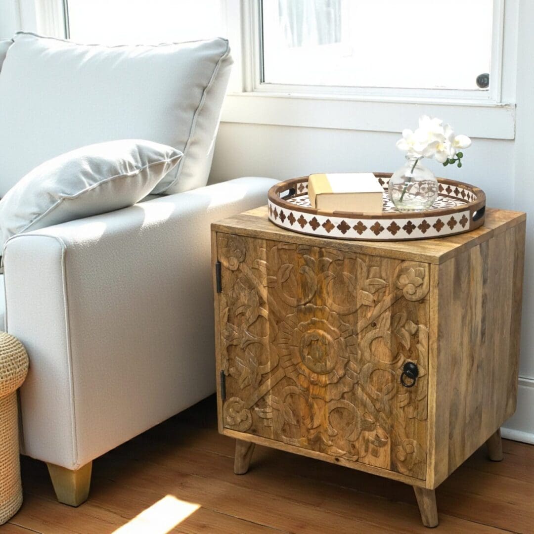 Hand-crafted solid wood side table cupboard with hand-carved door front and removable shelf. Staged in a living room